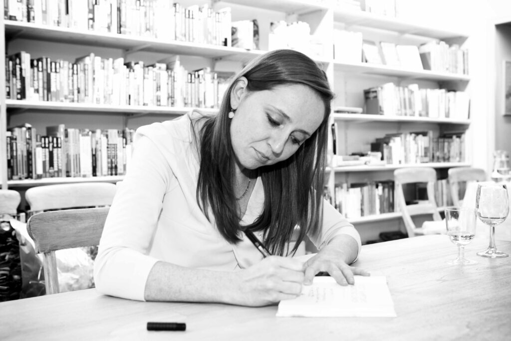 Vicky Hampton writing at a desk in front of bookshelves